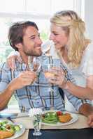 Cute smiling couple enjoying white wine over a meal together