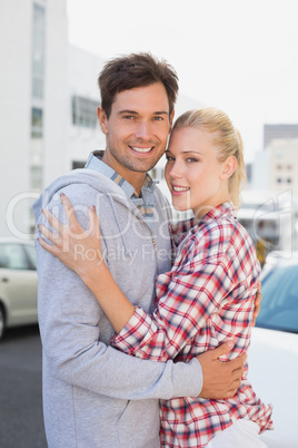 Hip young couple hugging smiling at camera