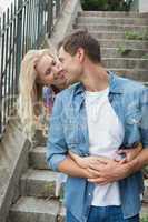 Hip young couple standing by steps hugging