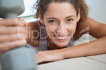 Fit woman smiling at camera holding dumbbell