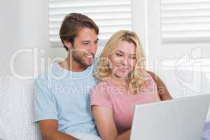 Happy couple relaxing together on the couch using laptop