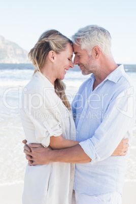 Happy couple hugging on the beach looking at each other