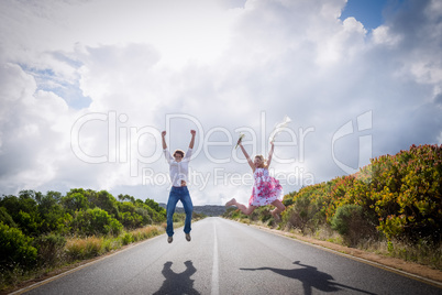 Excited couple jumping on the road