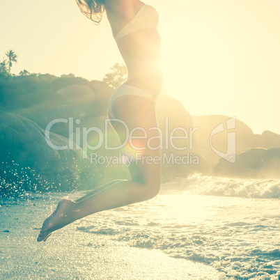 Beautiful jumping blonde in white bikini at the beach