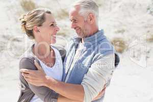 Happy couple hugging on the beach looking at each other