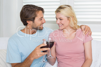 Happy couple drinking red wine together on the couch