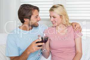 Happy couple drinking red wine together on the couch