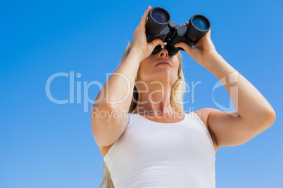 Blonde looking through binoculars on the beach