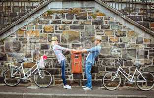 Hip young couple dancing by brick wall with their bikes