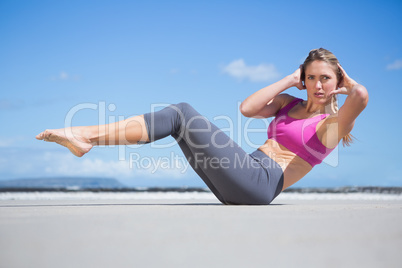 Focused fit blonde doing yoga on the beach