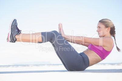 Fit blonde sitting in boat position on the beach