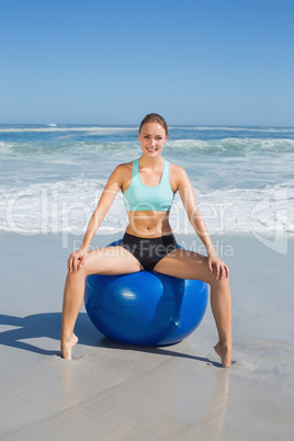 Fit woman sitting on exercise ball at the beach