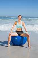 Fit woman sitting on exercise ball at the beach