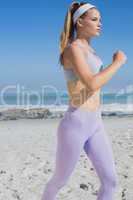 Sporty focused blonde jogging on the beach