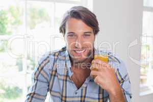 Casual smiling man having orange juice