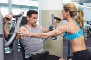 Personal trainer coaching bodybuilder using weight machine