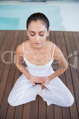 Peaceful brunette in white sitting in lotus pose