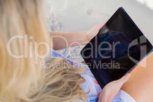 Woman sitting on beach in deck chair using tablet pc