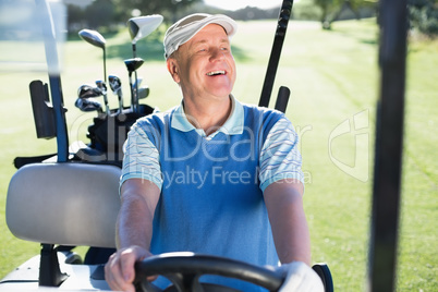 Happy golfer driving his golf buggy