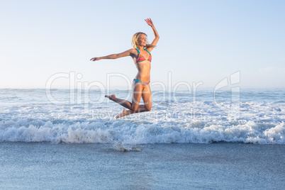 Happy blonde leaping on the beach in bikini