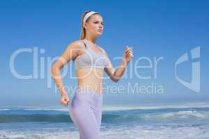 Sporty focused blonde jogging on the beach