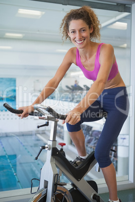 Pretty fit woman on the spin bike smiling at camera