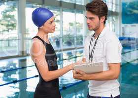 Swimmer discussing times with her coach by the pool