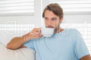 Handsome casual man sitting on couch having coffee