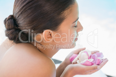 Smiling brunette lying on towel holding rose petals