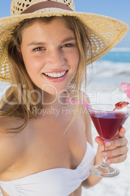 Pretty smiling blonde holding cocktail on the beach