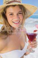 Pretty smiling blonde holding cocktail on the beach