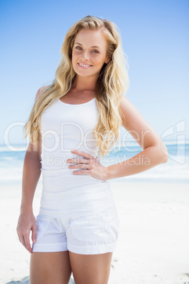 Gorgeous blonde smiling at camera on the beach