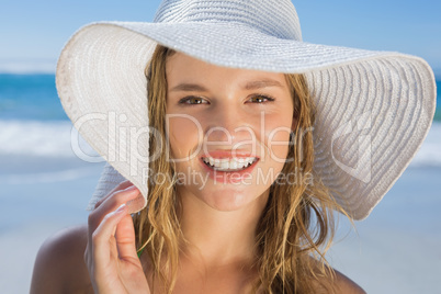 Beautiful girl in straw hat on the beach smiling at camera