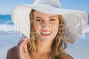 Beautiful girl in straw hat on the beach smiling at camera
