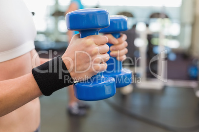Fit woman exercising with blue dumbbells