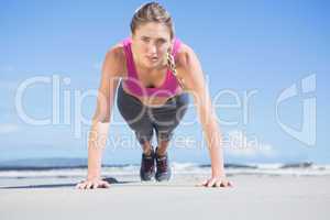 Fit blonde in plank position on the beach