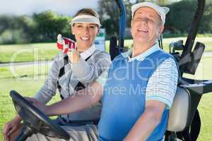 Happy golfing couple sitting in golf buggy looking around