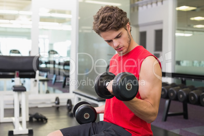 Fit man lifting heavy black dumbbells