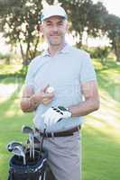 Handsome golfer standing with golf bag