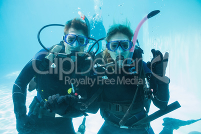 Friends on scuba training submerged in swimming pool looking to