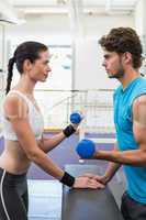 Fit focused couple exercising with blue dumbbells