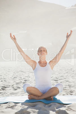 Peaceful woman sitting in lotus pose on beach