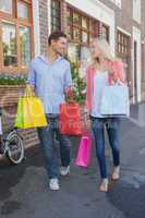 Stylish young couple walking with shopping bags