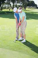 Man coaching his partner on the putting green