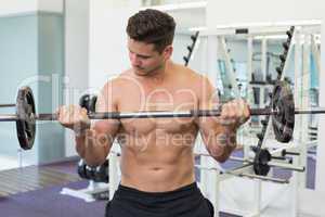 Shirtless bodybuilder lifting heavy barbell weight