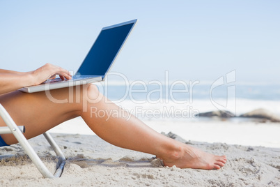 Woman sitting on beach using her laptop