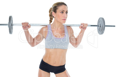 Strong female crossfitter lifting barbell behind head