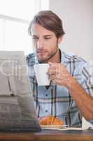Handsome man drinking coffee and reading newspaper