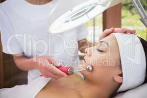 Peaceful brunette getting micro dermabrasion from beauty therapi