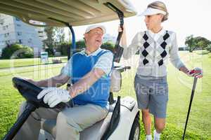 Happy golfing couple setting out for the day on buggy